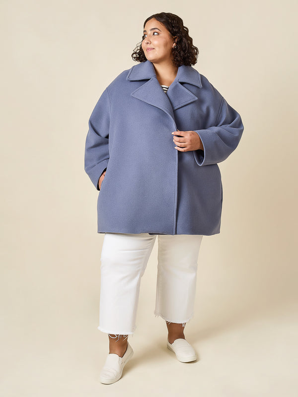 Plus-size sewn sample of the Phoebe coat sewing pattern by Closet Core Patterns in dusty blue wool with notched lapels, front view.